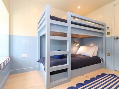 A bedroom with a blue bunk bed and a striped rug at Mavericks Wave in St Agnes