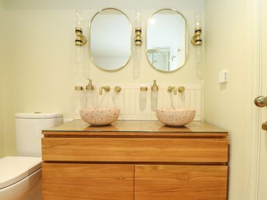 A bathroom with two round mirrors two vessel sinks and a wooden vanity at Mavericks Wave in St Agnes