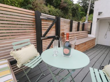 An outdoor area with a table, chairs, and a bottle of champagne at Mavericks Wave, St Agnes
