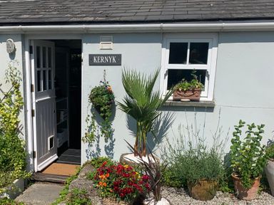The exterior of a white house with an open door a window flower pots and a sign that says Kernyk at Kernyk Carn Brea near Pool