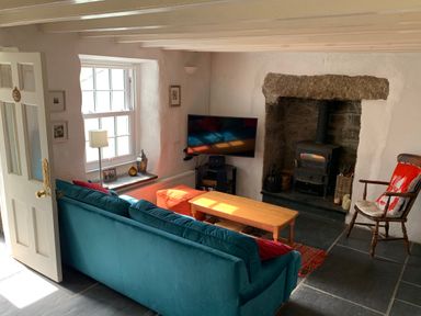 A living room with a teal sofa a wooden coffee table a wood burning stove and a rocking chair at Kernyk in Carn Brea near Pool
