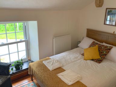A bedroom with a bed with pillows and folded towels near a window with plants at Kernyk in Carn Brea near Pool