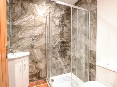 A bathroom with a glass shower enclosure a white sink cabinet and a toilet at The Old Dairy in Tittleshall near Brisley