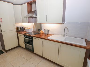 A kitchen with cabinets a stove oven a sink and countertop at Wood Cottage in Solva
