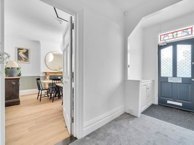 A hallway with a door and a view into the dining area at Palm House in Newquay