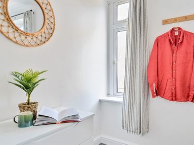 A bedroom with a mirror and shirt hanging at Palm House in Newquay