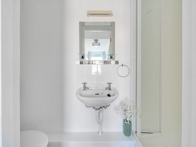 A bathroom with a sink and mirror at Palm House in Newquay