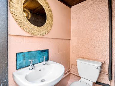 A bathroom with a sink, toilet, and mirror at Palm House in Newquay