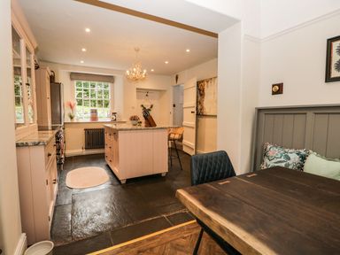 A kitchen with an island and a wooden dining table with chairs at Pear Tree Cottage in Grange-Over-Sands
