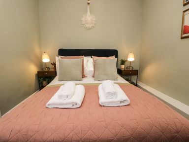 A bedroom with a bed with pillows and towels and two bedside tables with lamps at Pear Tree Cottage in Grange-Over-Sands