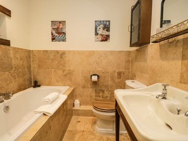 A bathroom with a bathtub sink and toilet with wooden seat at Pear Tree Cottage in Grange-Over-Sands