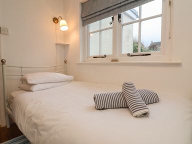 A bedroom with a white bed and pillows towels on bed near a window with blinds at Sunnymead in Bickington near Barnstaple