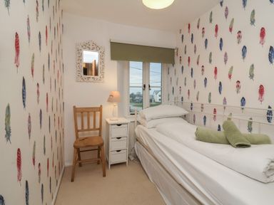 A small bedroom with a single bed white bedside table wooden chair and window at Sunnymead in Bickington near Barnstaple