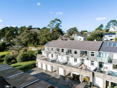 A row of townhouses with balconies and garages in front surrounded by trees at Slipway 14 in Rock