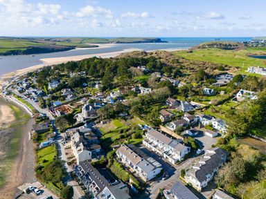 An aerial view of a coastal village with houses trees and a beach at Slipway 14 in Rock