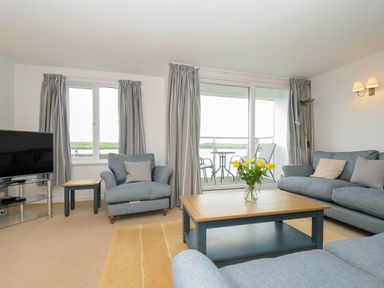 A living room with blue sofas a wooden coffee table with yellow flowers and a television at Slipway 14 in Rock