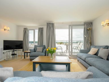A living room with sofas a coffee table TV and balcony doors at Slipway 14 in Rock