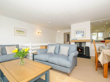 A living room with two blue sofas a wooden coffee table with yellow flowers and a fireplace at Slipway 14 in Rock