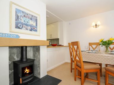 A dining area with a table set for four and a fireplace with a wood stove at Slipway 14 in Rock