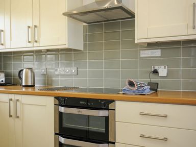 A kitchen countertop with kettle toaster oven and folded cloths on a rack at Slipway 14 in Rock