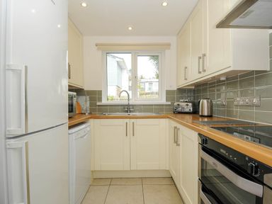 A kitchen with white cabinets wooden countertops a sink dishwasher oven toaster and kettle at Slipway 14 in Rock
