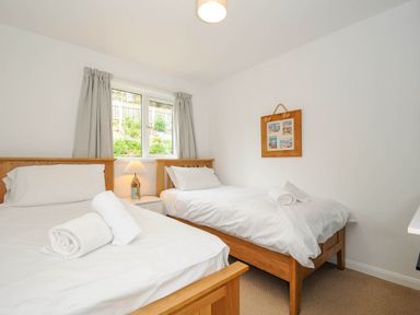 A bedroom with two single beds a window with curtains a bedside table with a lamp and a framed picture on the wall at Slipway 14 in Rock
