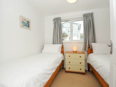 A bedroom with two single beds a chest of drawers between them and a window with curtains at Slipway 14 in Rock