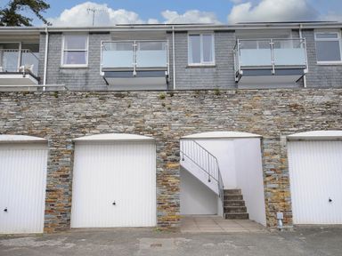 A building with grey stone lower level garages and stairs leading up to apartments with balconies at Slipway 14 in Rock