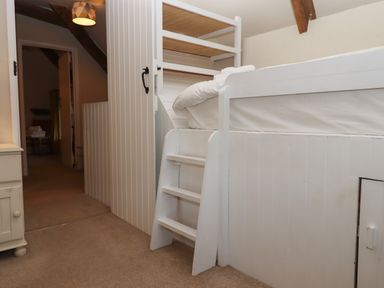 A bedroom with a white wooden bunk bed and a small staircase at Cherryblossom Cottage in Winkleigh