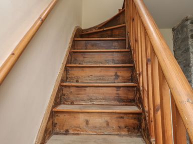 A wooden staircase with handrails and a stone wall at Ty Llugwy in Capel Curig near Betws-Y-Coed