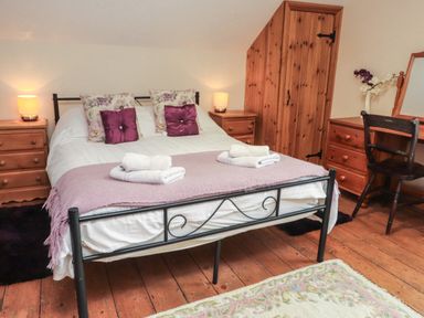 A bedroom with a double bed two bedside tables wooden wardrobe dressing table and chair at Ty Llugwy in Capel Curig near Betws-Y-Coed