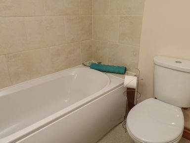 A bathroom with a bathtub and a toilet with a toilet paper holder at Ty Llugwy in Capel Curig near Betws-Y-Coed