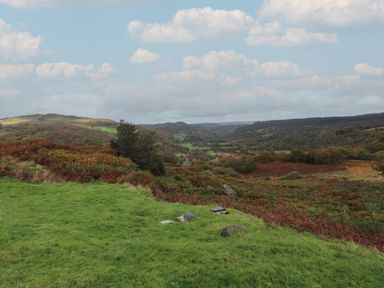 A hilly landscape with green grass and trees under a cloudy sky at Ty Llugwy in Capel Curig near Betws-Y-Coed