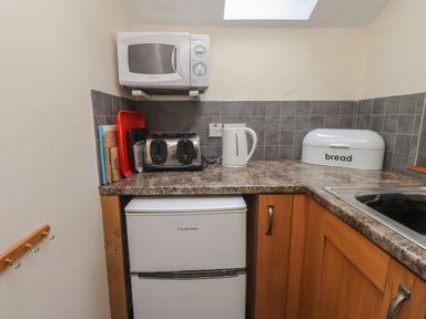 A small kitchen corner with a microwave oven toasters kettle bread box and fridge at Ty Siabod in Capel Curig near Betws-Y-Coed
