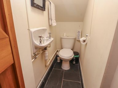 A small bathroom with a toilet sink hand towel and trash bin at Ty Siabod Capel Curig near Betws-Y-Coed