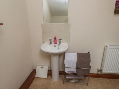 A bathroom sink with two towels on a metal rack a white scale and a radiator at Ty Siabod in Capel Curig near Betws-Y-Coed