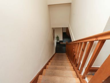 A wooden staircase with a railing leading down to a hallway with a plant in Capel Curig near Betws-Y-Coed
