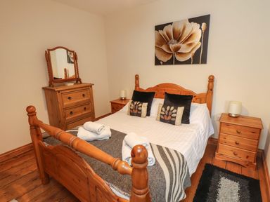 A bedroom with a wooden bed frame chest of drawers and bedside tables at Ty Siabod in Capel Curig near Betws-Y-Coed