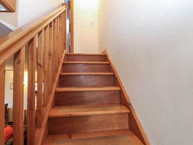 A wooden staircase with a handrail on the left side at Ty Llewelyn in Capel Curig near Betws-Y-Coed