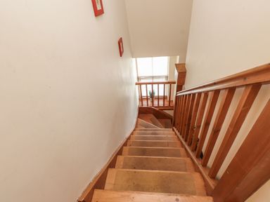 A wooden staircase with a railing and a window with blinds at Ty  Llewelyn in Capel Curig near Betws-Y-Coed
