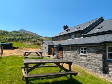An outdoor area with a house and picnic tables at Ty Llewelyn Capel Curig near Betws-Y-Coed