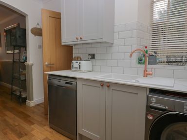A kitchen with a countertop toaster dishwasher washing machine and a sink with a faucet at 1 Boarbank Farm in Allithwaite near Cartmel
