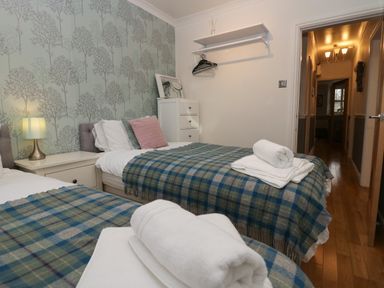 A bedroom with two single beds covered with plaid blankets and white towels at 1 Boarbank Farm in Allithwaite near Cartmel