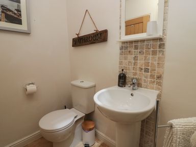 A bathroom with a toilet a white pedestal sink mirror and a wooden sign that says bathroom at 1 Boarbank Farm Allithwaite near Cartmel