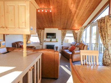 A living room with leather sofas a wooden dining table and chairs under a wooden ceiling at Kellet Lodge Lakeside 26 in Dock Acres near Carnforth