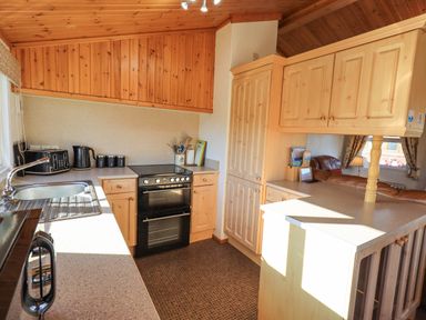 A kitchen with wooden cabinets a black oven a sink toaster kettle and canisters at Kellet Lodge Lakeside 26 Dock Acres near Carnforth
