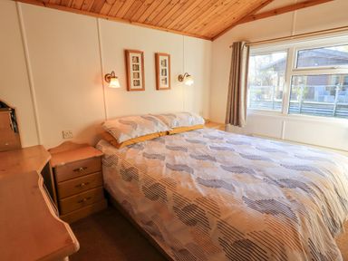 A bedroom with a double bed bedside tables a dressing table and a window at Kellet Lodge Lakeside 26 Dock Acres near Carnforth