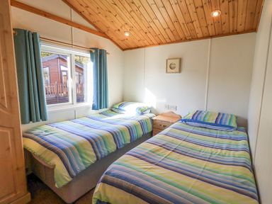 A bedroom with two single beds with striped bedding and a bedside table between them at Kellet Lodge Lakeside 26 Dock Acres near Carnforth