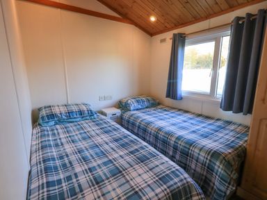 A bedroom with two single beds and a window with curtains at Kellet Lodge Lakeside 26 Dock Acres near Carnforth