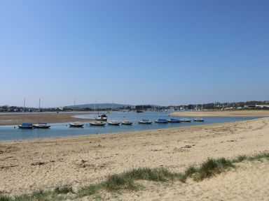 A sandy beach with small sailboats anchored in shallow water at 117 Crosswinds in Hillway near Bembridge